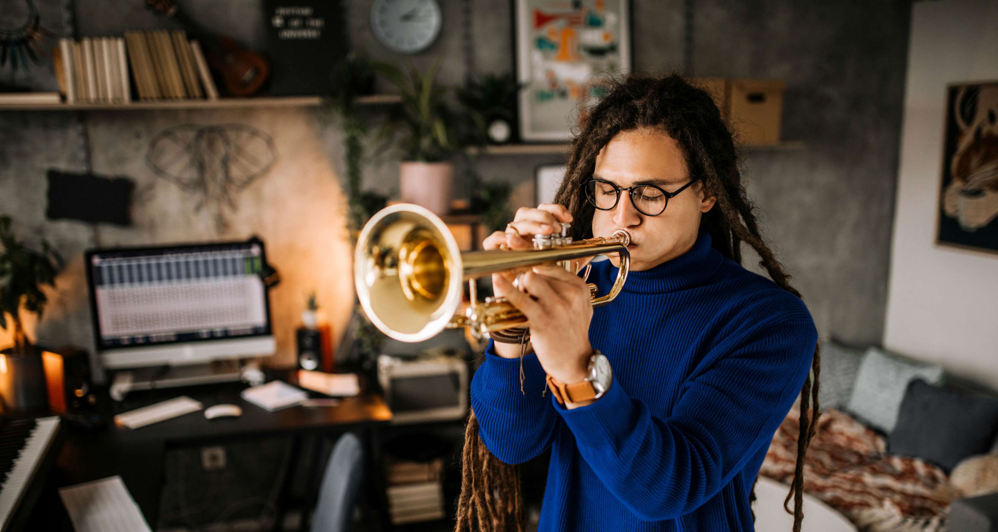 Instrumentenversicherung: Junger Mann spielt Trompete im Wohnzimmer