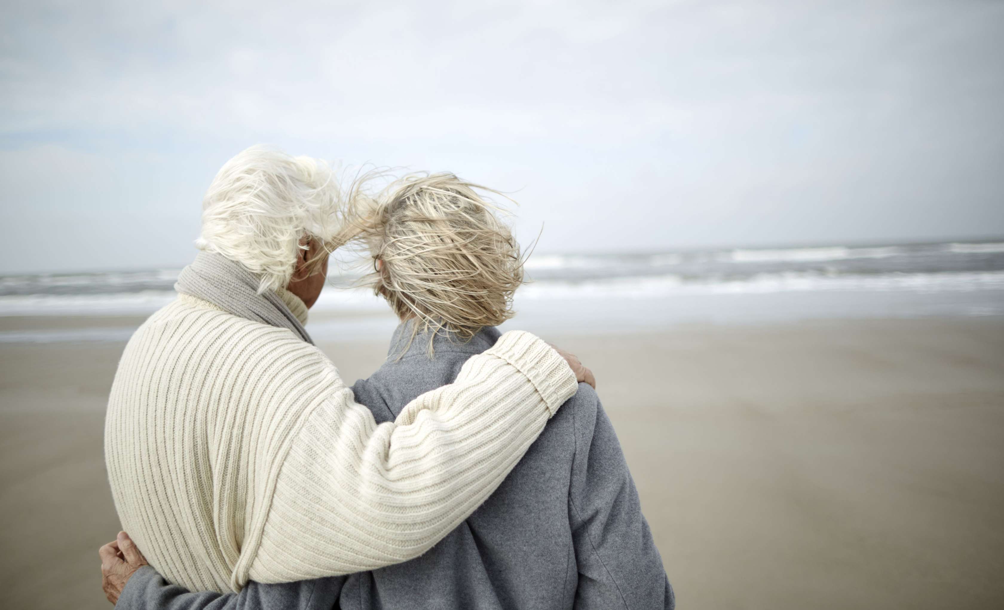 Sterbegeldversicherung - Ein altes Ehepaar steht am Stand und schaut in die Ferne.