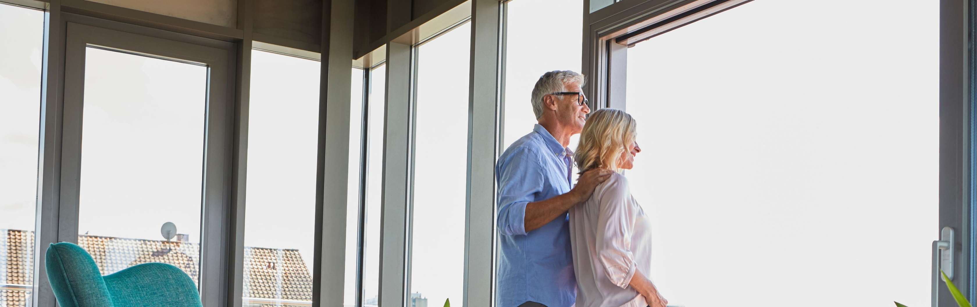 Sterbegeldversicherung Einmalzahlung - Ein Mann und eine Frau stehen im Haus vor einem Fenster und blicken gemeinsam nach draußen.