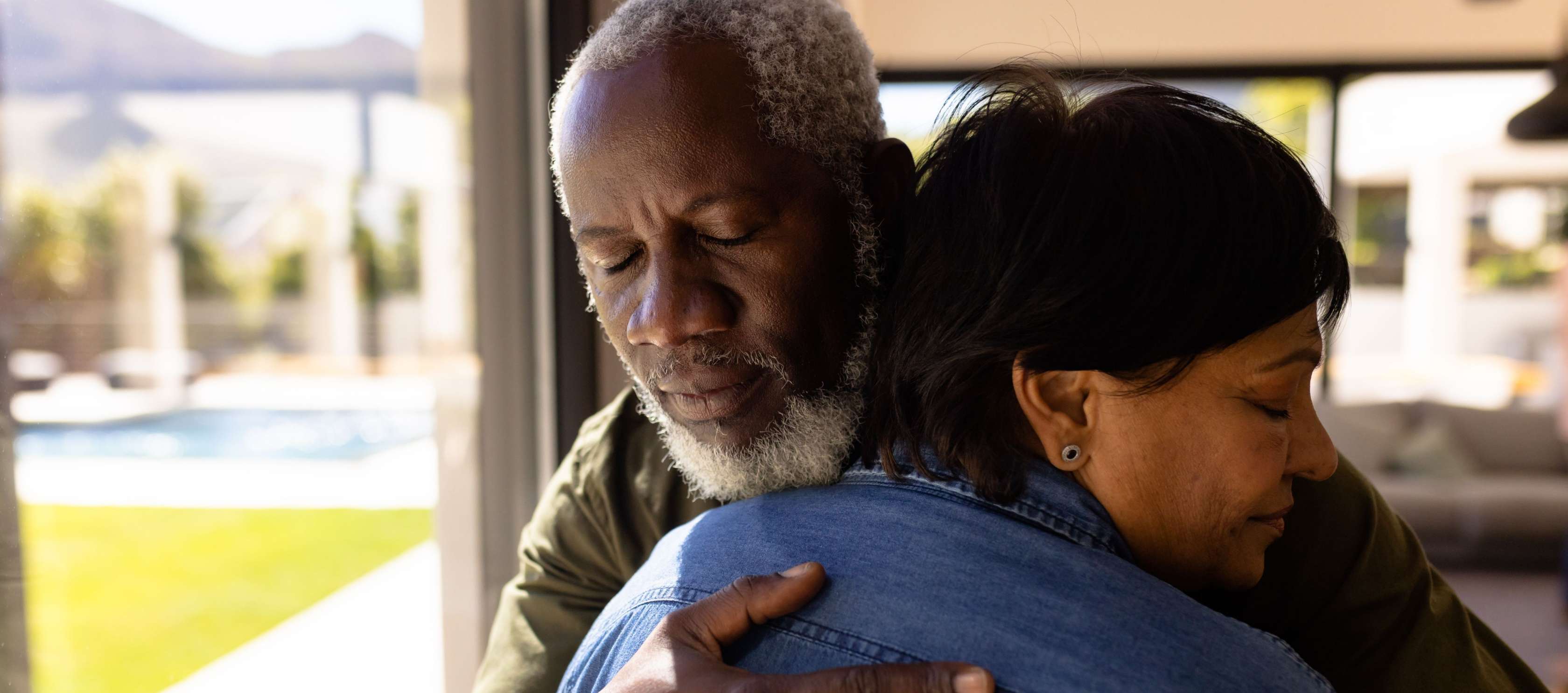 Sterbegeldversicherung für Eheleute - Ein älterer Mann umarmt seine Frau und hat dabei die Augen geschlossen.